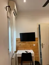 Armario abierto de madera con perchas y una caja fuerte en la base